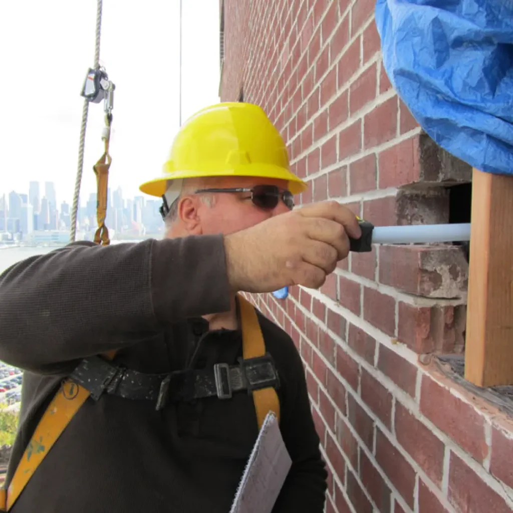 a person wearing a hard hat and yellow hard hat repairing balcony railing