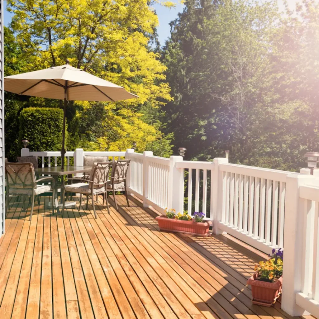 a deck with a table, white railing and umbrella