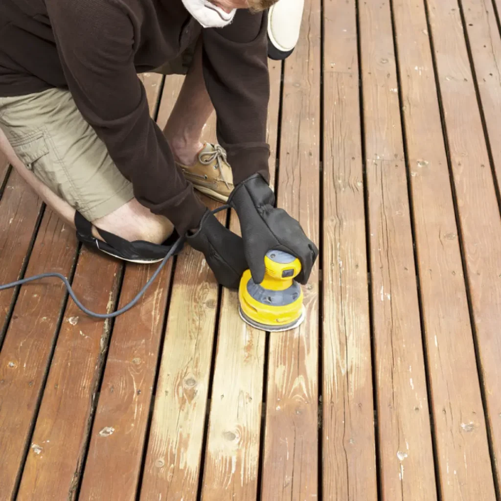 a person sanding a wood deck